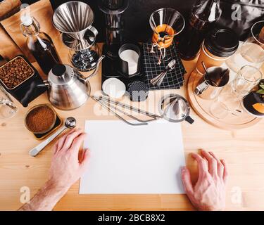 https://l450v.alamy.com/450v/2bcb8x2/the-mans-hands-hold-a-white-blank-sheet-of-paper-copy-space-accessories-and-utensils-for-making-coffee-using-alternative-methods-wooden-table-in-t-2bcb8x2.jpg