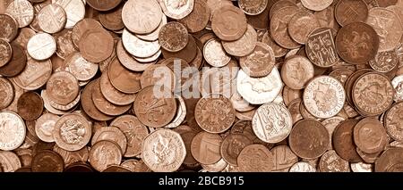 UK currency, hundreds of British copper and silver colored coins randomly piled ontop of each other, one pound coins, fifty pence, twenty pence, two p