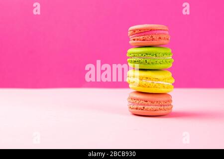 Multi-colored macaroons stand in a pile on a pink table Stock Photo