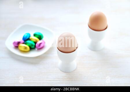 eggs in stands and small chocolate eggs in multi-colored wrappers on a platter Stock Photo