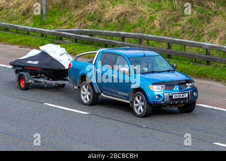 2008 blue Mitsubishi L200 Diamond DI-D D/C A towing Jet Ski trailer; Vehicular traffic moving vehicles, driving vehicle on UK roads, motors, motoring on the M6 motorway highway Stock Photo