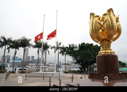 Hong Kong, China. 4th Apr, 2020. Chinese national flag and the flag of the Hong Kong Special Administrative Region (SAR) fly at half-mast to mourn for martyrs who died in the fight against the novel coronavirus disease (COVID-19) outbreak and compatriots who died of the disease in Hong Kong, south China, April 4, 2020. Credit: Li Gang/Xinhua/Alamy Live News Stock Photo