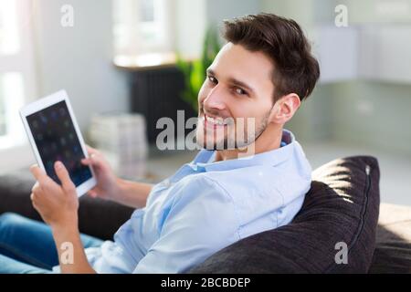 Man sitting on couch with digital tablet Stock Photo
