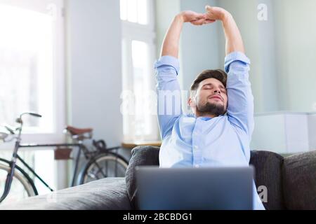 Man sitting on couch with laptop Stock Photo