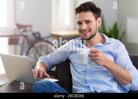 Man sitting on couch with laptop Stock Photo