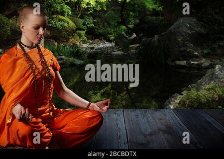 Beautiful young woman in orange robe sits in meditation  in the  garden on wood floor..Meditation is the best way to solve the most complex problem. Stock Photo