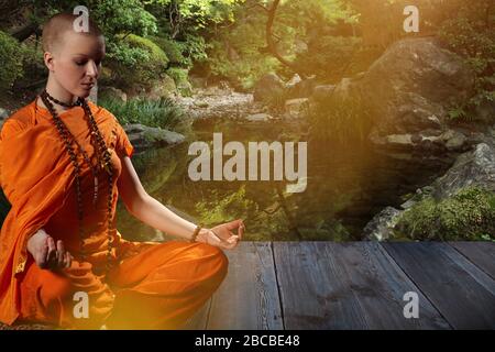 Beautiful young woman in orange robe sits in meditation  in the  garden on wood floor..Meditation is the best way to solve the most complex problem. Stock Photo