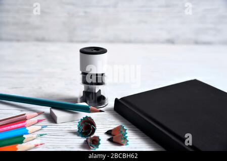 Pencils, notepad, sharpener, eraser and shavings from pencils on a gray non-uniform background Stock Photo