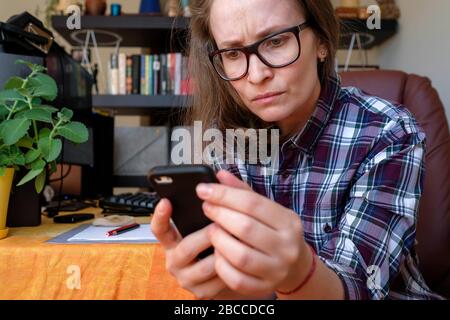 A woman is reading bad information from a gadget. Negative emotions. Stay home. Stock Photo