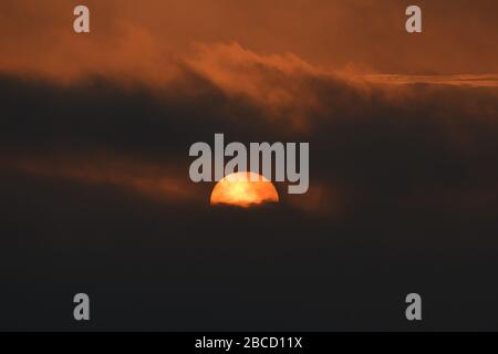 Big colorful setting sun in the clouds in Peru Stock Photo