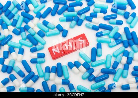 NHS letters tiles & assorted blue pills. Metaphor NHS in Covid 19 pandemic, NHS heroes, NHS prescriptions, UK National Health Service, medicine in UK