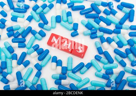 NHS letters tiles & assorted blue pills. For NHS 75th birthday, NHS heroes, NHS prescriptions, UK National Health Service, medicine in UK Stock Photo