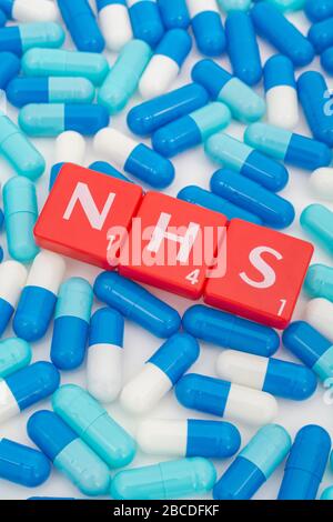 NHS letters tiles & assorted blue pills. For NHS 75th birthday, NHS heroes, NHS prescriptions, UK National Health Service, medicine in UK Stock Photo