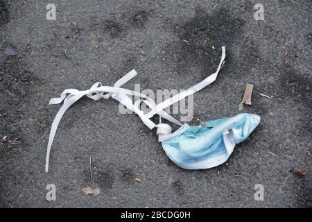 A discarded surgical face mask lying in the street Stock Photo