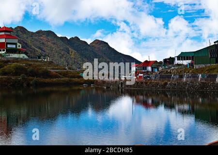 A landscape view of Tsomgo Lake, also called Changu Lake surrounded by stony hills and roads in Autumn season under blue sky. A sacred location for lo Stock Photo