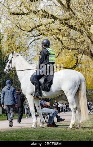 Hamburg, Germany. 04th Apr, 2020. A mounted policeman points out to people in a park on the Outer Alster that, as part of the contact ban to contain the coronavirus, it is forbidden to sit outside on meadows or benches. Credit: Markus Scholz/dpa/Alamy Live News Stock Photo