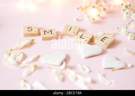 Word SMILE in wooden letter tiles against a soft pink background - still life concept Stock Photo