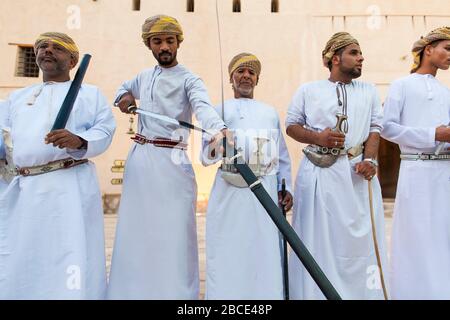 Traditional Omani sword dancers perform with musicians demonstrating inherited skills at Nizwa Fort, Nizwa, Oman Stock Photo