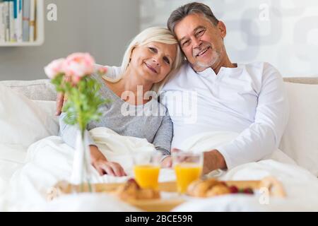 Senior couple enjoying breakfast in bed Stock Photo