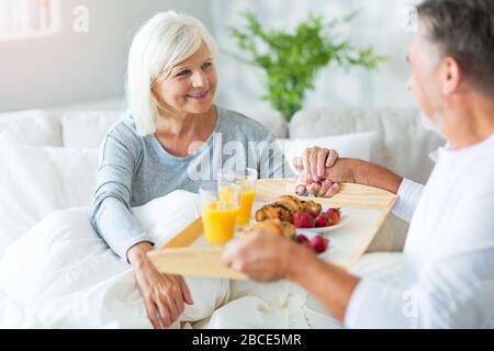 Senior couple enjoying breakfast in bed Stock Photo
