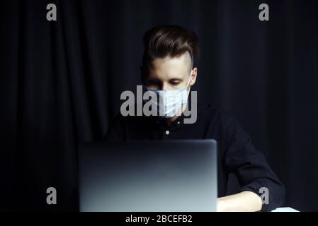 The young guy is studying distance learning and talks on the webcam at home in the evening. The concept of self-isolation due to the coronavirus pandemic. Stock Photo