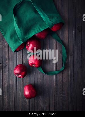 Online shopping delivery. Eco friendly bag with red apples on dark wooden background Stock Photo