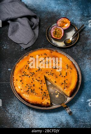 Homemade mango upside down cake with passion fruit and metal pie server on dark rustic background. Selective focus. Stock Photo