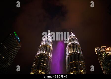 Multi-colored dancing fountains near the twin towers of Petronas in Kuala Lumpur. Stock Photo