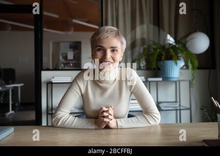 Portrait of happy attractive young businesswoman sitting at table. Stock Photo