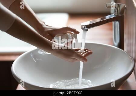 Young cautious woman applying antibacterial soap on hands. Stock Photo