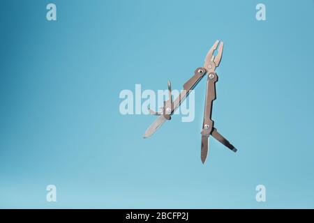 The multitool multi-function tool hovers on a blue background. The concept of an expanded multi-tool with free space. Clipping path included isolate Stock Photo