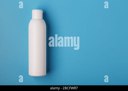 White bottle of cream on a blue background with space for text. Free space for text. The view from the top Stock Photo
