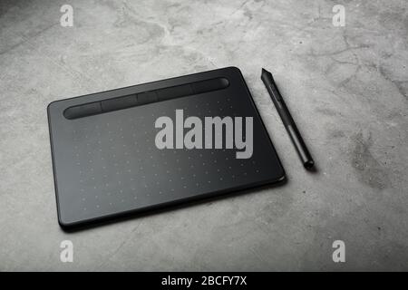 Graphic tablet with a stylus on a dark textural background, top view. Gadget for working as a designer, artist and photographer. Stock Photo