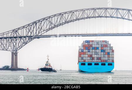 container vessel leaving the Panama Canal and passing the bridge of the Americas, the only road connection between north and south America Stock Photo