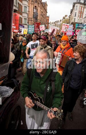 Protester playing a ukulele during an Anti-Austerity march in London Stock Photo