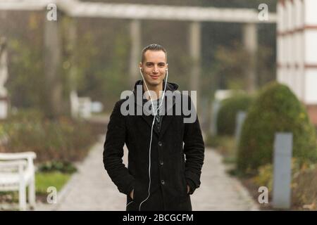 Portrait of Young Man with Earphones Standing Outdoors Stock Photo