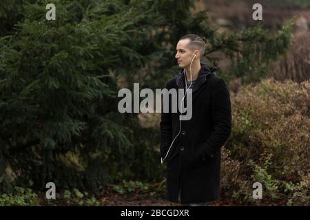 Profile of Young Man with Earphones in Autumnal Park Background Stock Photo