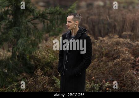 Young Man Listening to Earphones in Park Profile View Stock Photo