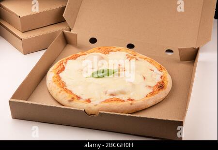Pizza inside open box on tall stack of delivery boxes close up Stock Photo