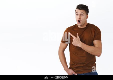 Omg so cool look there. Portrait of amazed and speechless adult handsome man, gasping and staring at left side, seeing incredible best deal for online Stock Photo