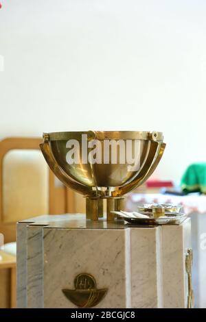 The decoration of the Roman Catholic church. Filled with holy water and gilded cup-shaped baptismal font one hundred on the presbytery in the church. Stock Photo