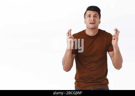 Nervous and hopeful man praying to god, making wish with fingers