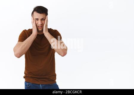 Man going insane on self-isolation quarantine during coronavirus pandemic. Portrait of distressed and tensed adult guy feel stress and panic, squeez Stock Photo