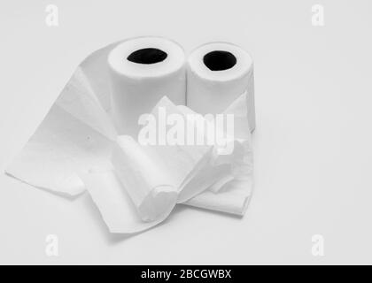 Two rolls of white toilet paper on white background, partly unrolled, viewed from an angle