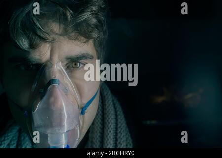 Dark Portrait of man using steam vapor inhaler nebulizer doing aerosol inhalation medicine treatment at home or hospital flu and asthma bronchitis vir Stock Photo