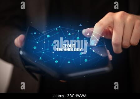 Businessman holding a foldable smartphone with CLOUD TECHNOLOGY inscription, new technology concept