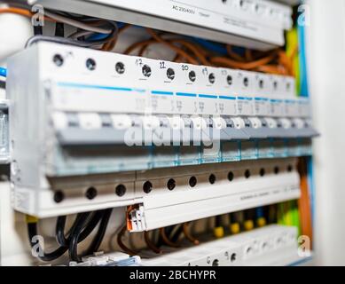 Single-phase fuses and three-phase fuses in the OFF position, placed in the home fuse box, visible electric wires. Stock Photo