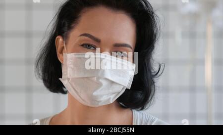 Happy smiling female wearing protective medical face mask. Stock Photo