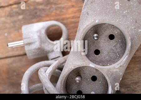 Old dirty extender on a wooden table. Electrical accessories in the workshop. Light background. Stock Photo