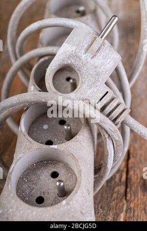 Old dirty extender on a wooden table. Electrical accessories in the workshop. Light background. Stock Photo
